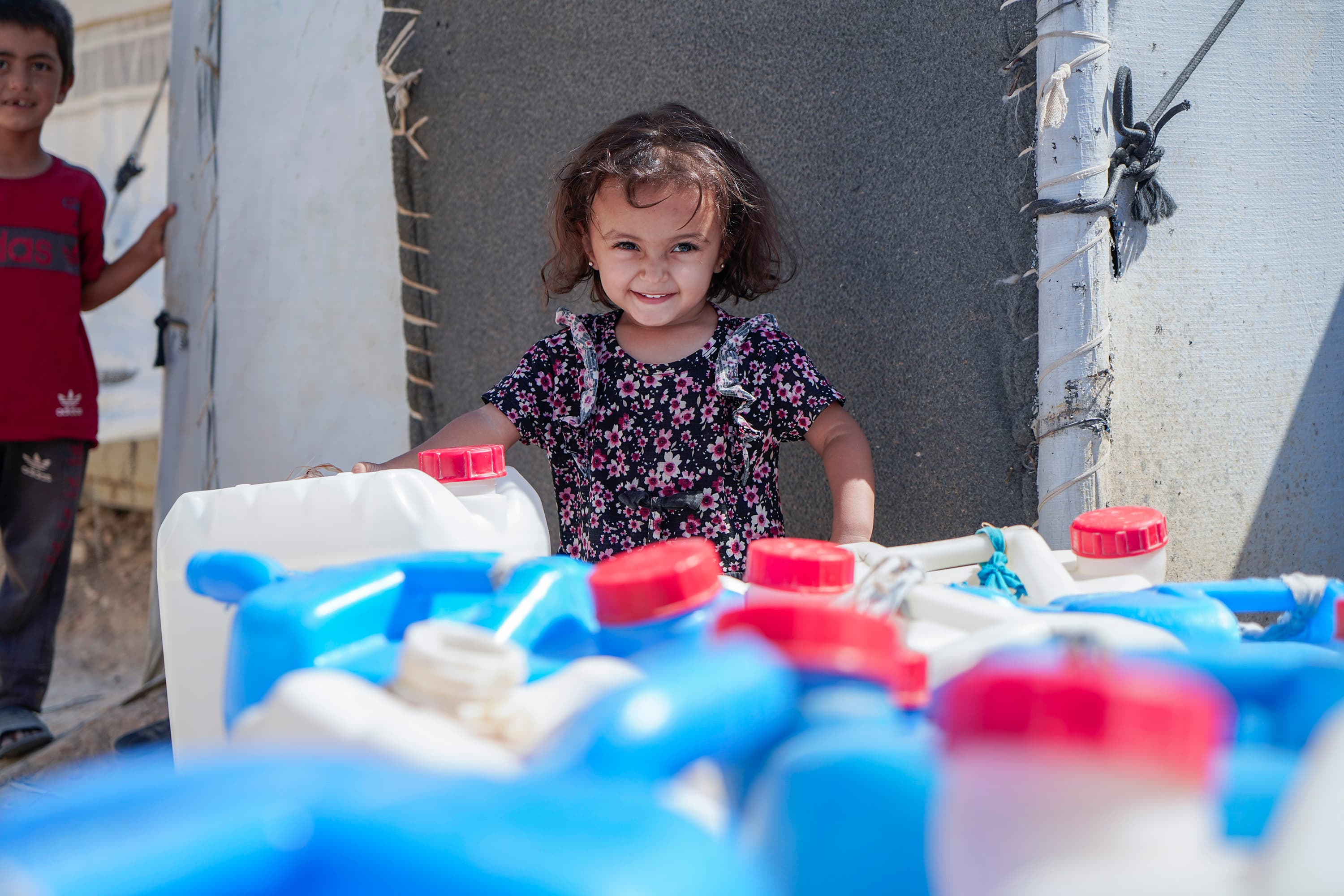 Glad flicka med vattendunkar - Syrien 2024